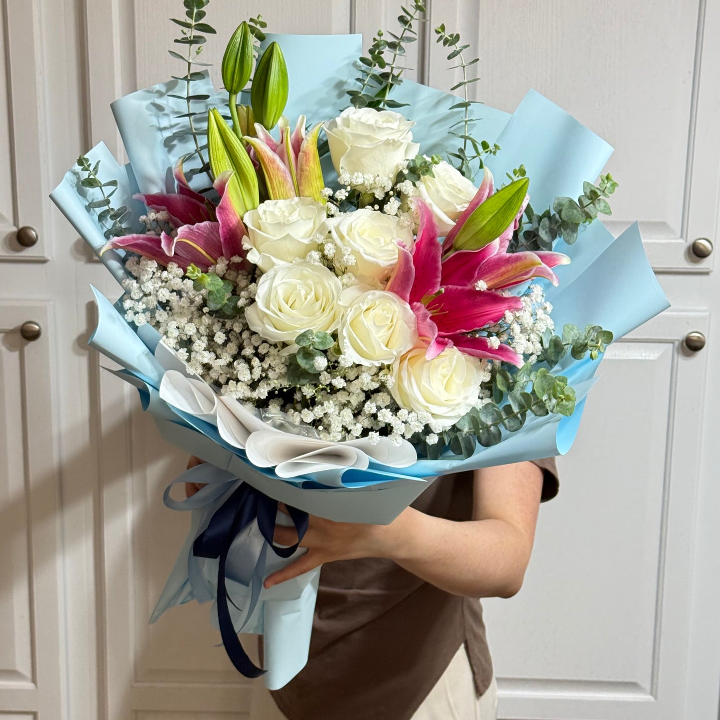 Close-up of a vibrant bouquet with white roses, pink lilies, and baby's breath.