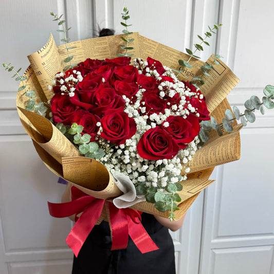 Beautiful red roses and white baby's breath in vintage newspaper-wrapped bouquet.