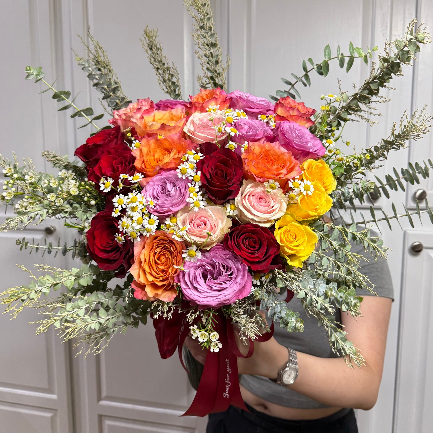 Large, colorful rose bouquet with red, orange, pink, yellow, and purple flowers.