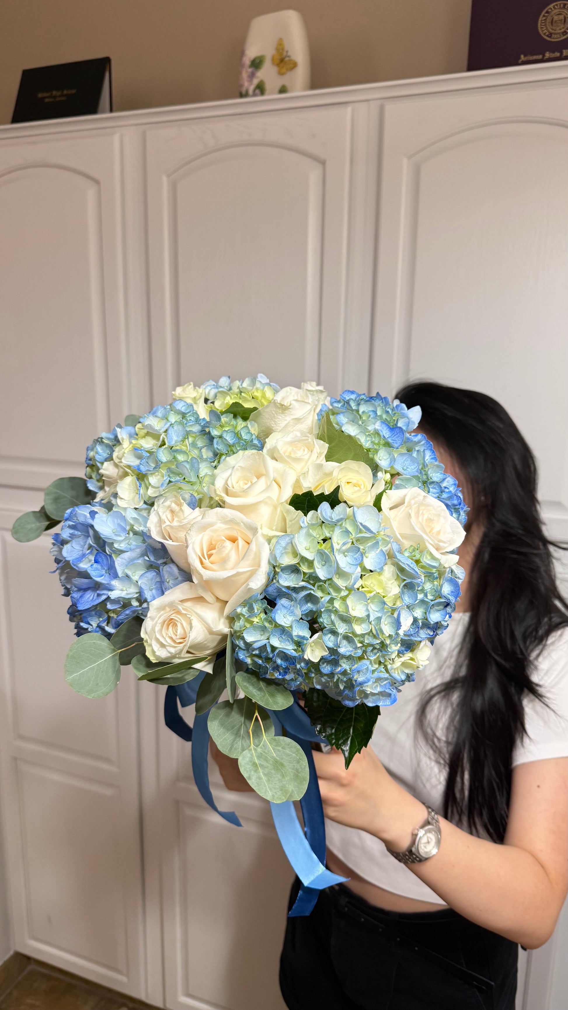 Blue hydrangea and white rose bouquet with eucalyptus and blue ribbons.