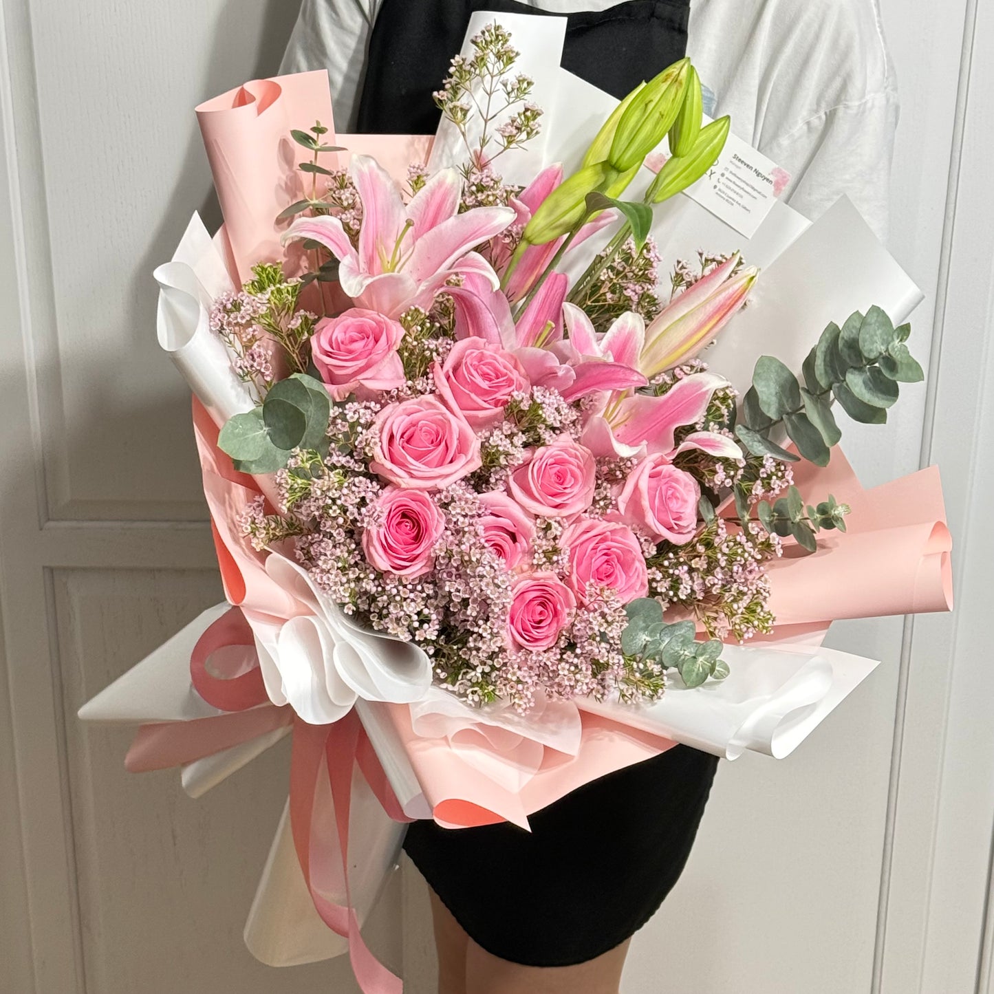 Large pink rose and lily bouquet wrapped in pink and white paper.