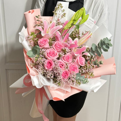 Large pink rose and lily bouquet wrapped in pink and white paper.
