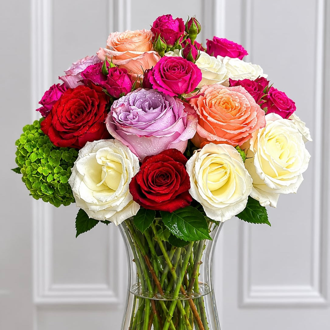 A vibrant bouquet of fresh multi-colored roses in a clear glass vase.
