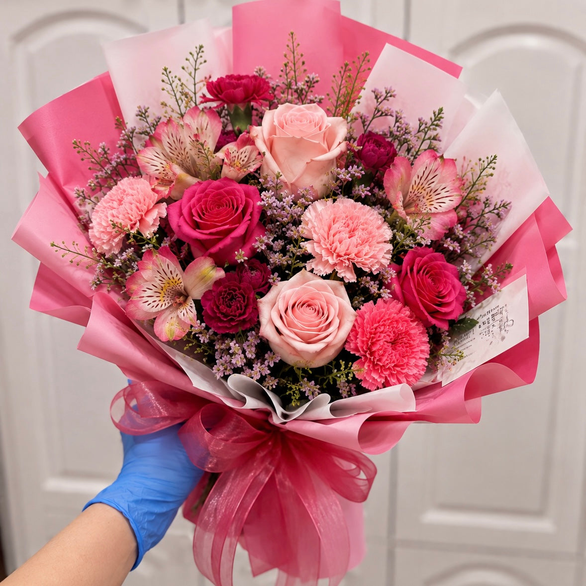 A vibrant pink and fuchsia floral bouquet featuring roses, carnations, and alstroemeria.