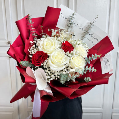 Elegant red and white rose bouquet with delicate filler flowers.