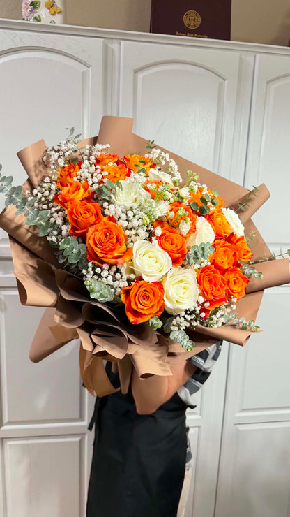 Vibrant orange and white roses in a large, brown-wrapped bouquet.