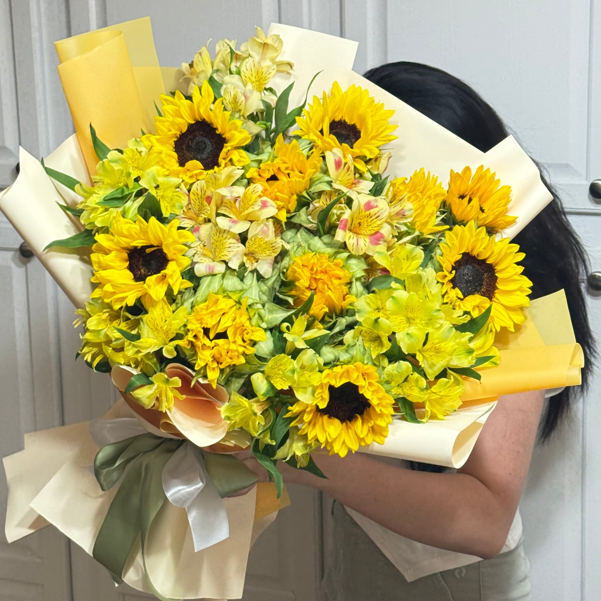 Bright yellow sunflower bouquet with other flowers, wrapped in cream and yellow paper.