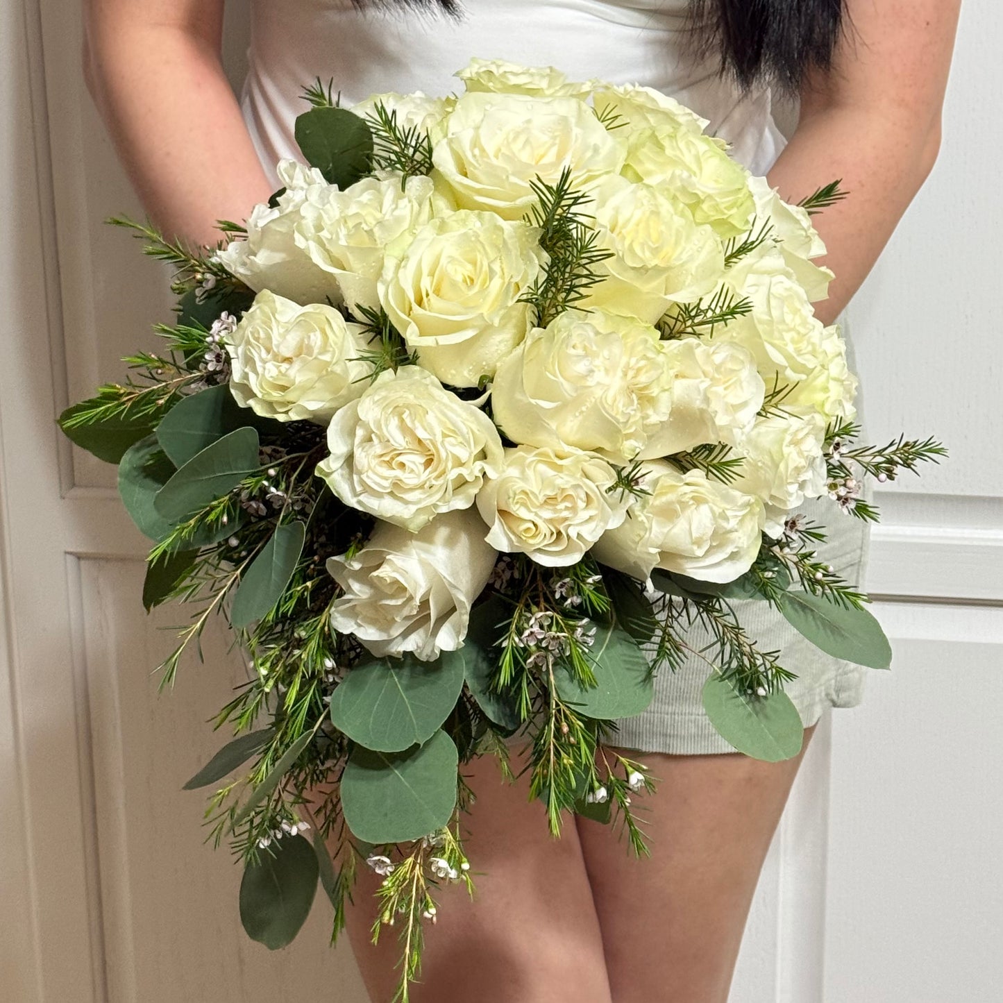 Elegant cascading white rose bouquet with fresh green eucalyptus leaves.
