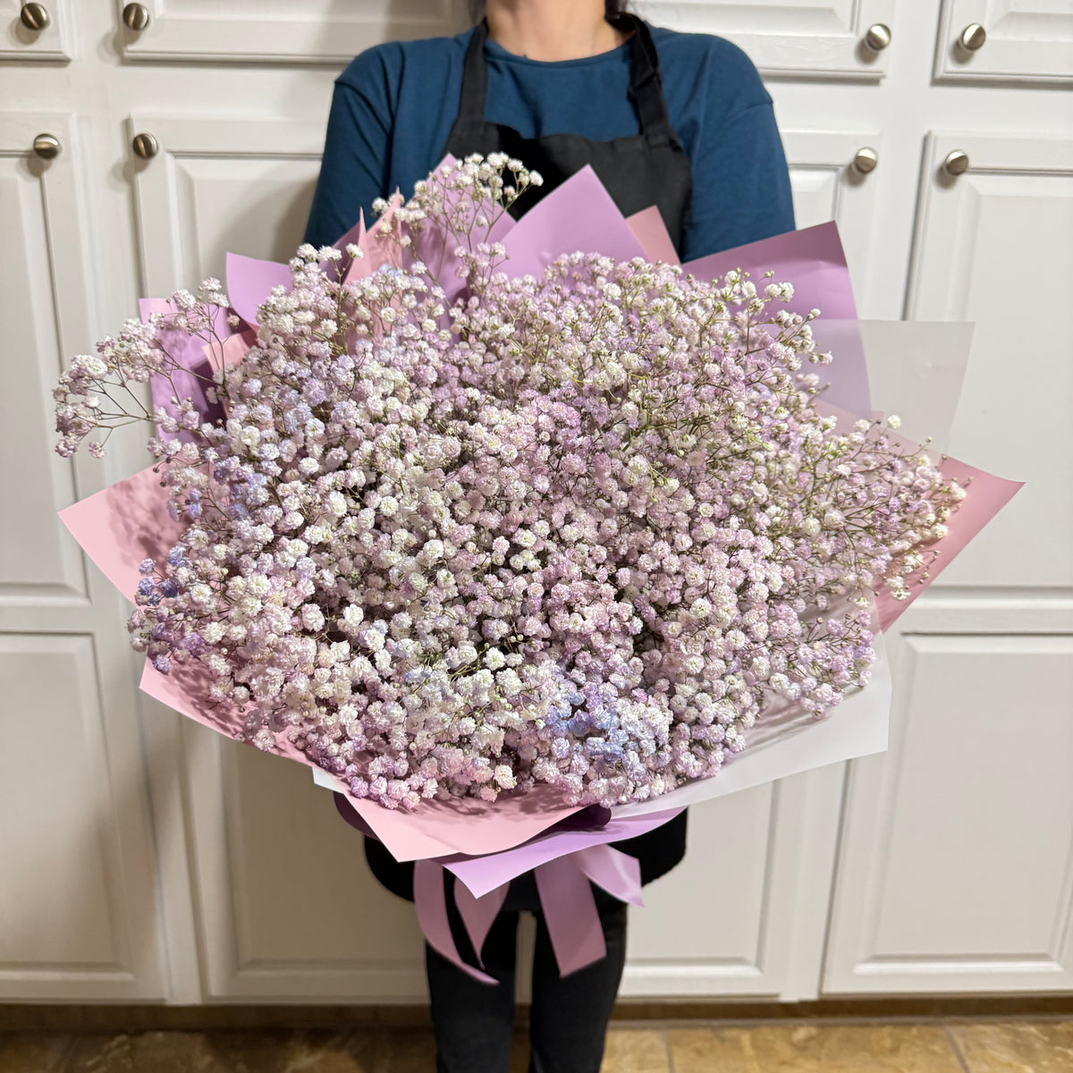 Large bouquet of delicate pink, purple, and white baby's breath flowers wrapped in paper.