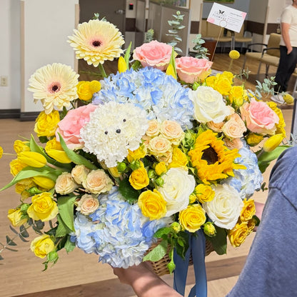 Vibrant Easter floral basket with yellow, blue, pink flowers and a white dog.