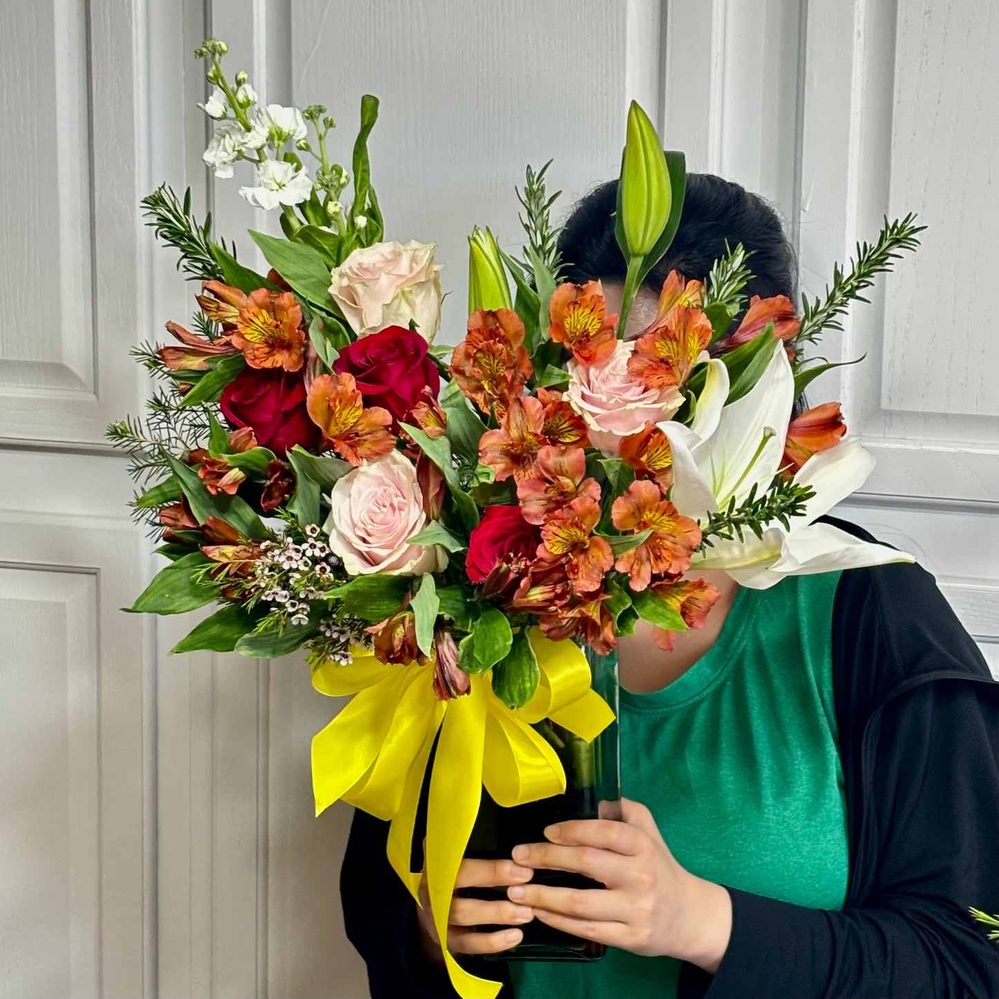 Vibrant bouquet of red, pink, orange, and white flowers with a yellow ribbon.