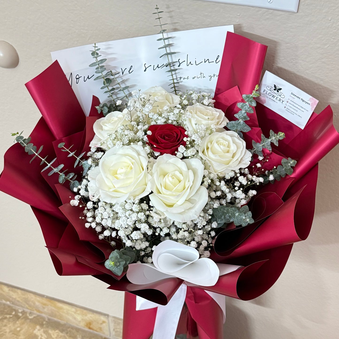 A dreamy bouquet of white and red roses wrapped in red paper.