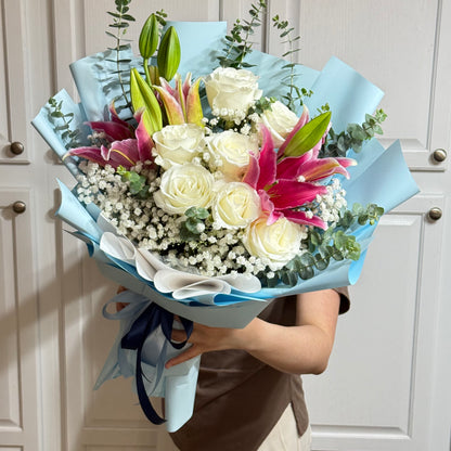 Close-up of a vibrant bouquet with white roses, pink lilies, and baby's breath.
