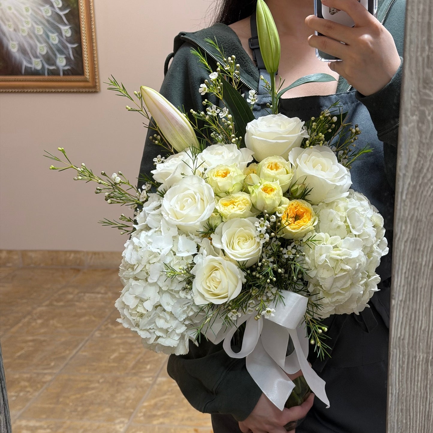 Large white and yellow floral arrangement with roses, hydrangeas, and a lily bud.