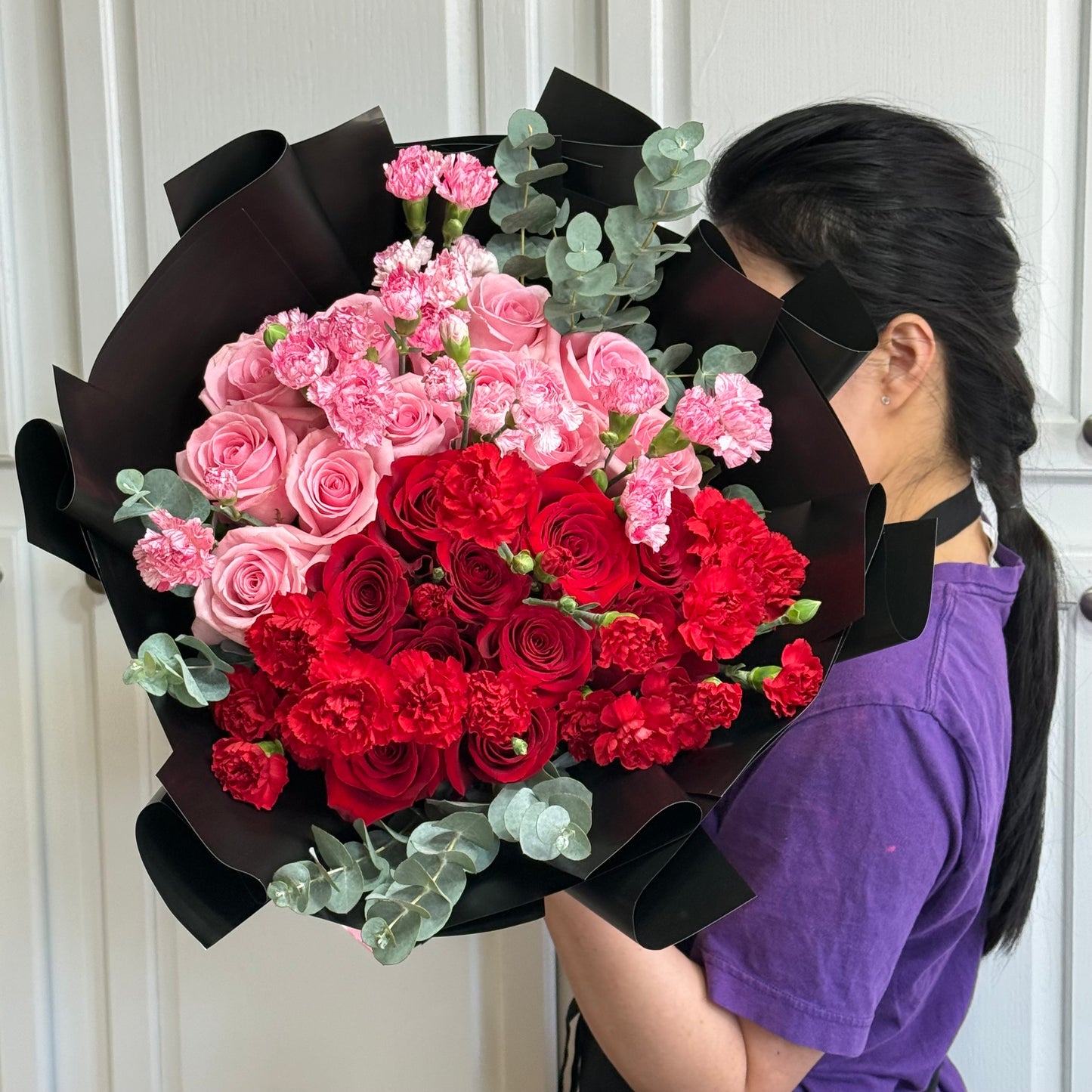 Beautiful bouquet of pink and red roses and carnations wrapped in black.
