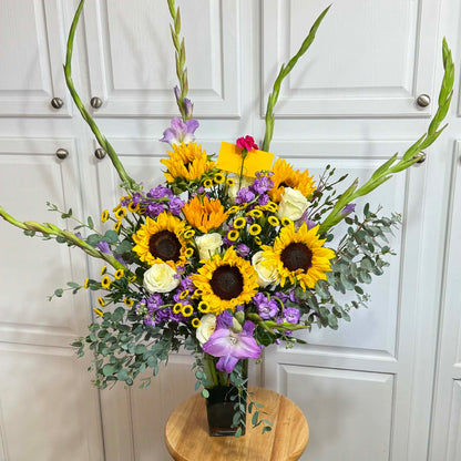 Stunning bouquet of yellow sunflowers, white roses, and purple gladiolus in a vase.