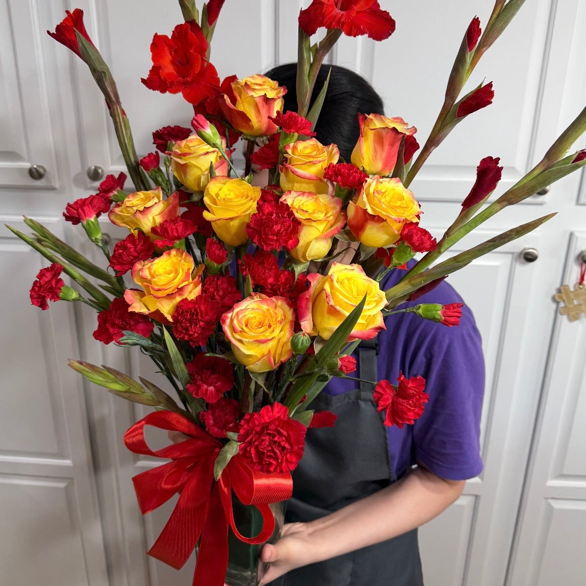 Vibrant red and yellow rose bouquet with gladiolus and carnations.