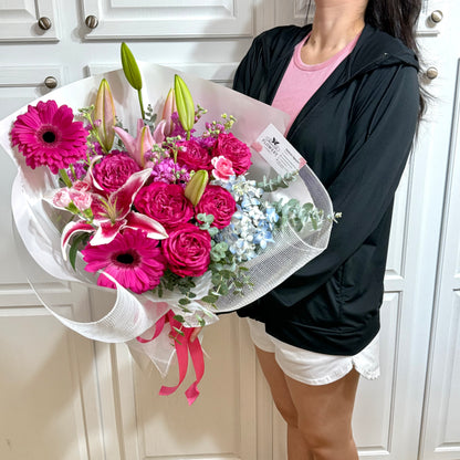 Vibrant pink and blue floral bouquet with roses, lilies, and gerberas.