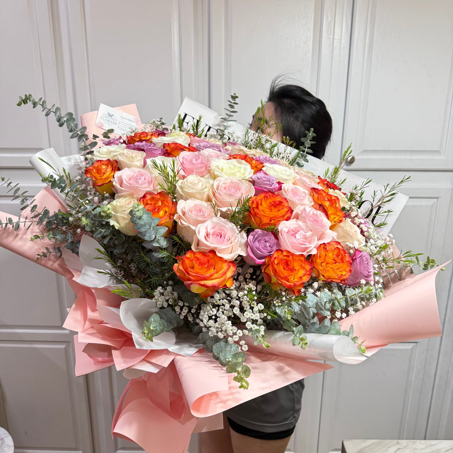 Vibrant bouquet of orange, pink, white, and purple roses with greenery.