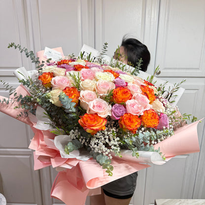 Vibrant bouquet of orange, pink, white, and purple roses with greenery.