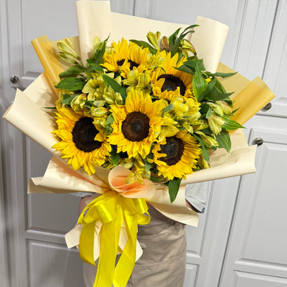 Vibrant bouquet of yellow sunflowers and green flowers with a yellow ribbon.