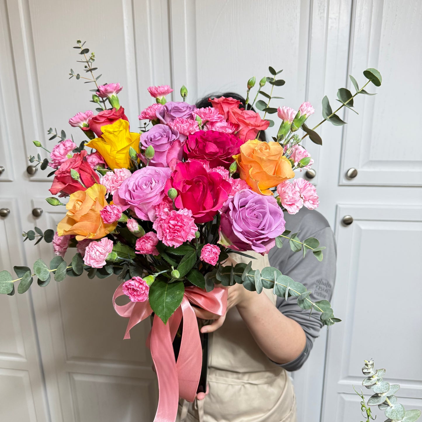Vibrant bouquet of colorful roses and pink carnations with eucalyptus.