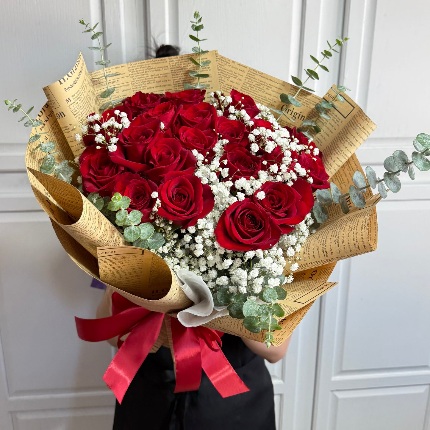 Beautiful red roses and white baby's breath in vintage newspaper-wrapped bouquet.