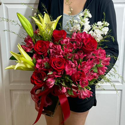 A lovely bouquet featuring red roses, yellow lilies, and white flowers.