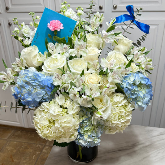 Vibrant blue and white flower bouquet with roses, hydrangeas, and a blue ribbon.