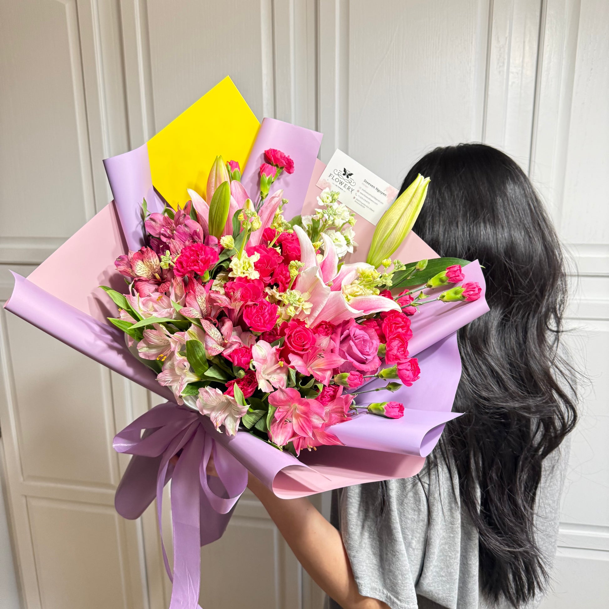 Large pink and fuchsia floral bouquet with lilies, roses, and lavender wrap.