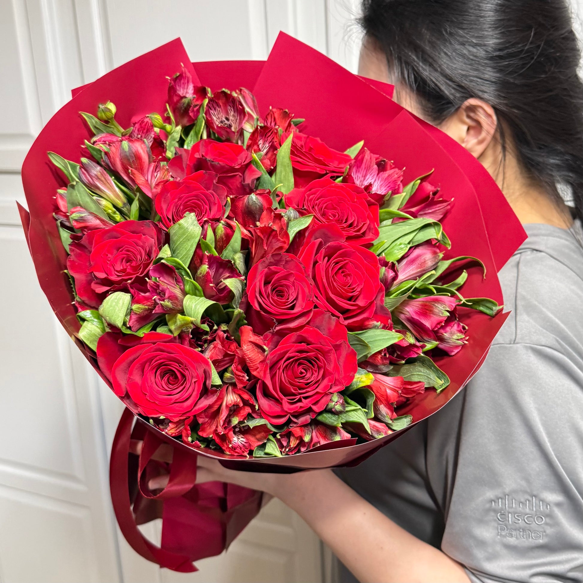 Crimson red rose and alstroemeria bouquet wrapped in red paper.