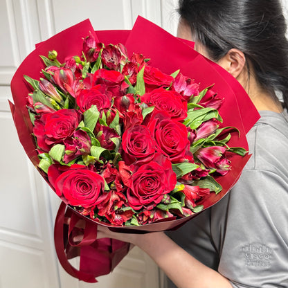 Crimson red rose and alstroemeria bouquet wrapped in red paper.